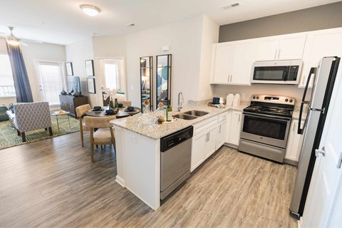 A kitchen with white cabinets and a wooden floor.