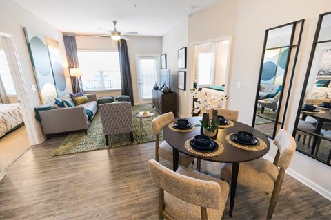 A dining room with a table set for two and a couch.