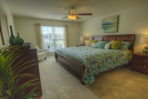 A bedroom with a bed, dresser, and ceiling fan.