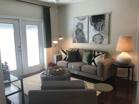 A living room with a grey couch, a coffee table, and a painting on the wall.