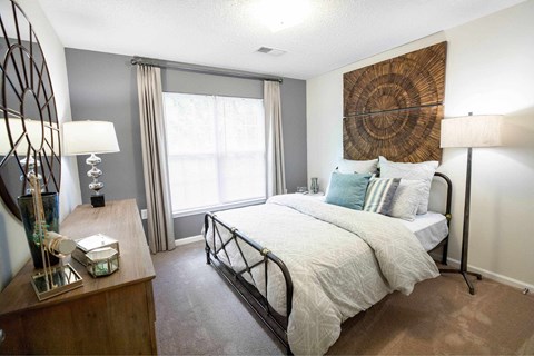 A bedroom with a large bed and a wooden dresser.