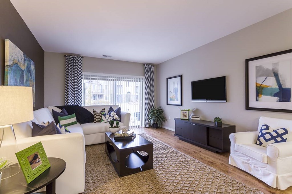 A living room with a white couch, a black coffee table, and a painting on the wall.