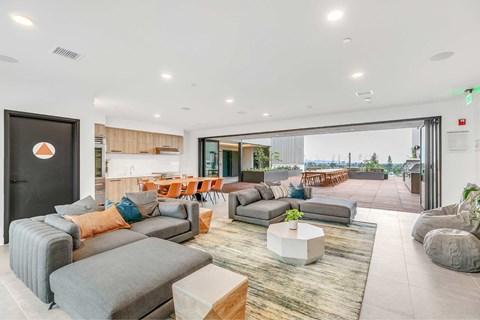 A modern living room with grey and orange couches and a large window.