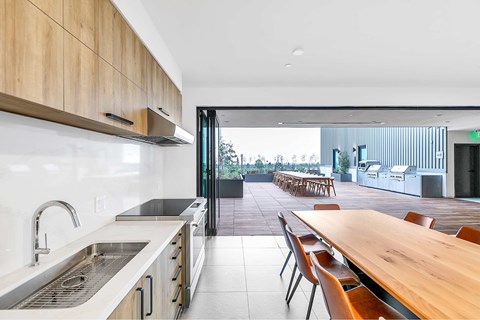 A modern kitchen with a long wooden table and chairs.