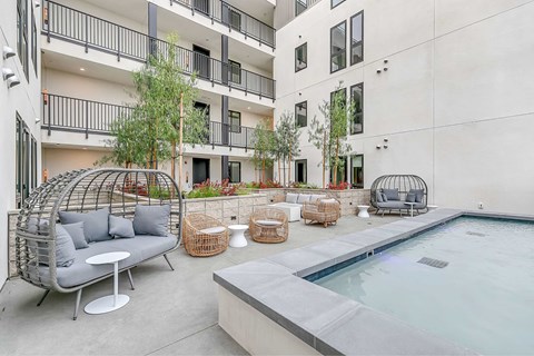 A modern outdoor seating area with a pool and a building in the background.
