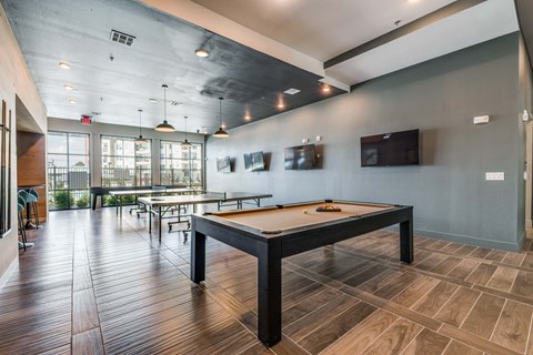 A room with a pool table and a bar area.