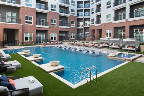 A large outdoor swimming pool surrounded by lounge chairs and umbrellas.