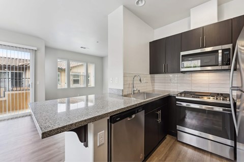 A modern kitchen with dark brown cabinets and stainless steel appliances.