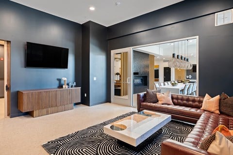 A modern living room with a brown leather couch and a black and white rug.