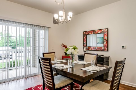 A dining room with a table set for two and a chandelier hanging from the ceiling.