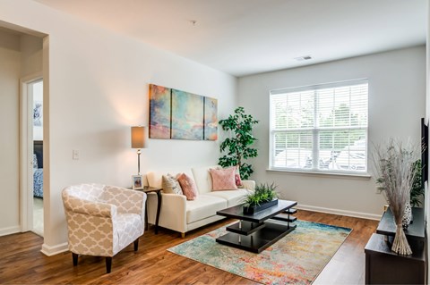 A living room with a white couch, a chair, a coffee table, and a painting on the wall.
