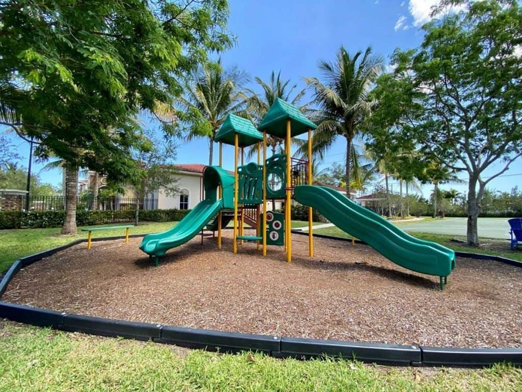 A playground with a green slide and a yellow structure.