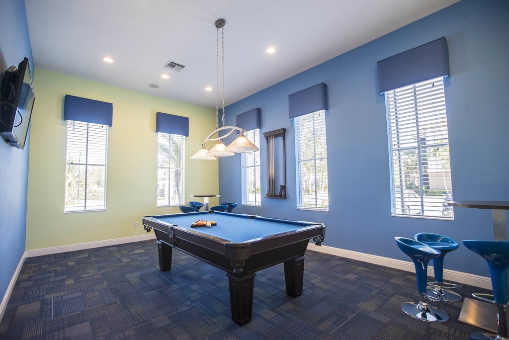 A pool table in a room with blue walls and a television mounted on the wall.