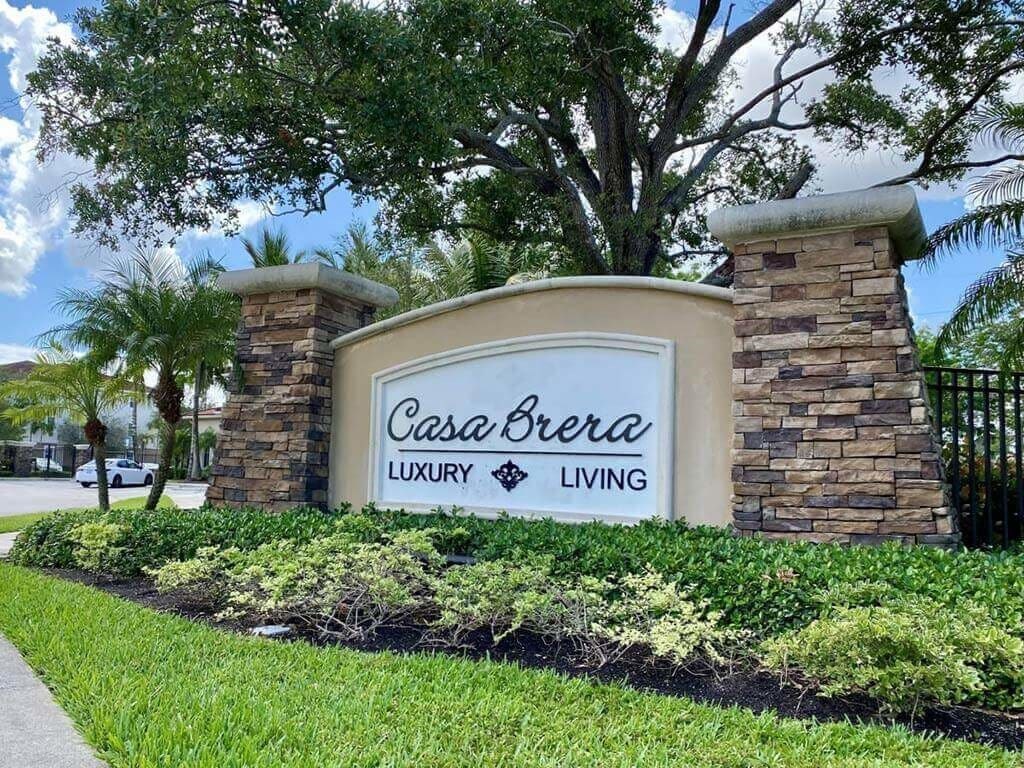 A sign for Casa Brera Luxury Living is displayed in front of a landscaped area.