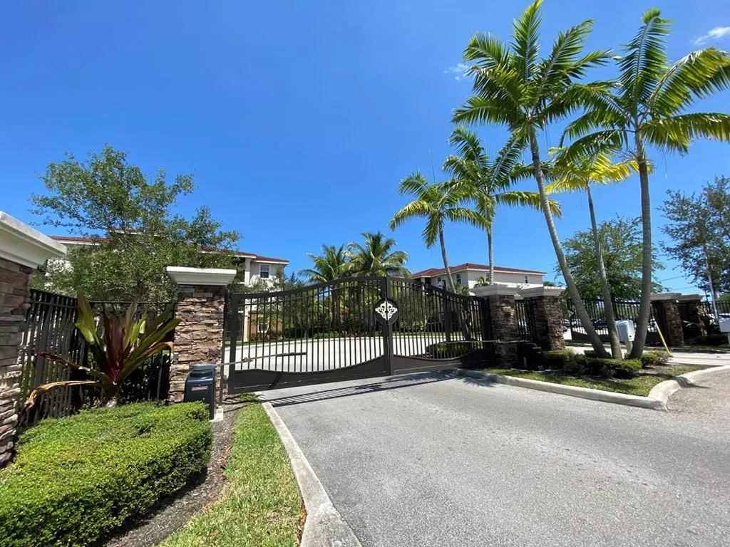 A gated entrance to a residential area with a palm tree.