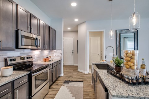 A modern kitchen with dark wood cabinets and granite countertops.