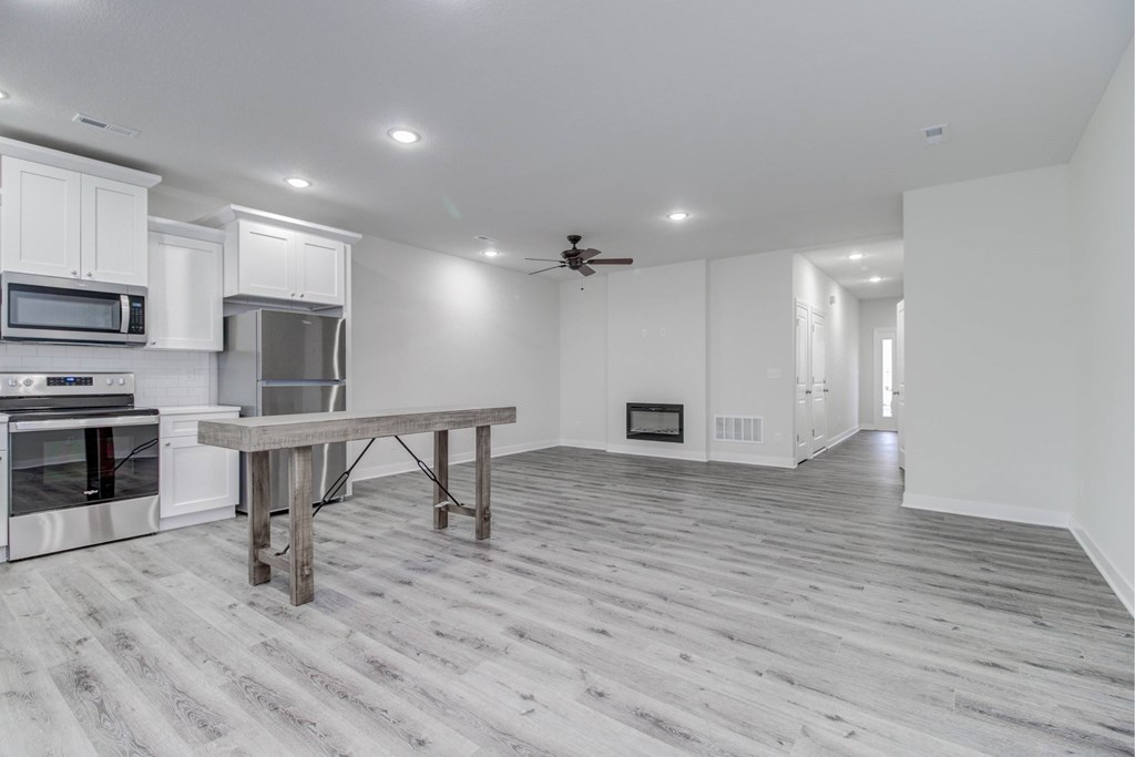 A spacious kitchen with a dining table and a ceiling fan.