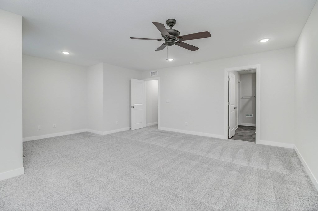 A room with a ceiling fan and carpeted floor.
