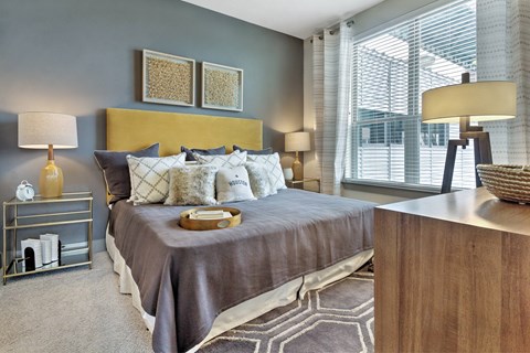 A bedroom with a large bed and a nightstand with a lamp.