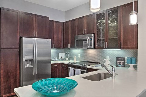 A kitchen with brown cabinets and a stainless steel refrigerator.
