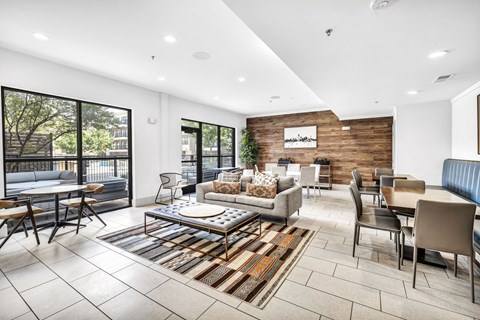 A modern living room with a large rug and a variety of seating options.