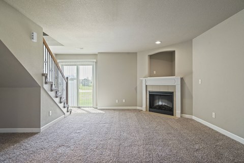 A living room with a fireplace and a staircase.