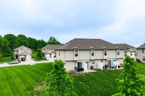 A large white house with a grey roof and a green lawn in front.