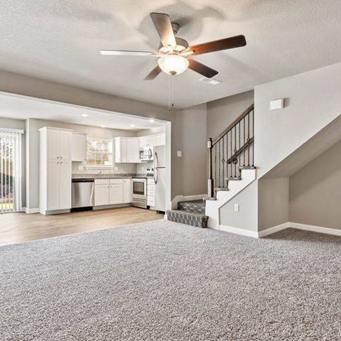 A spacious living room with a staircase leading to the upper floor.