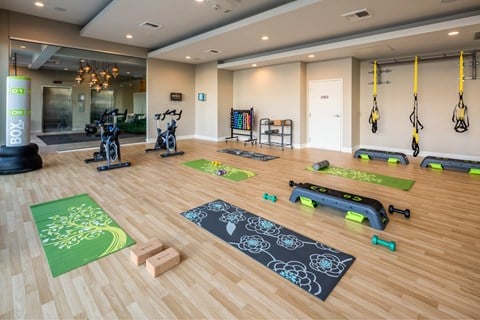 A gym with exercise equipment and yoga mats.