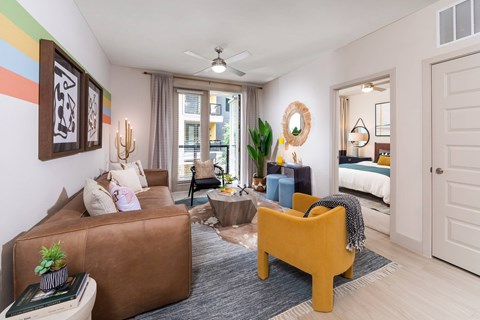 A living room with a brown couch, a yellow chair, and a ceiling fan.