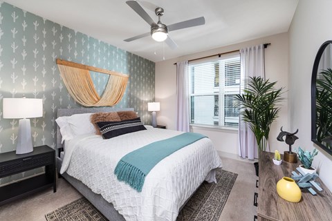 A bedroom with a bed, a ceiling fan, and large window