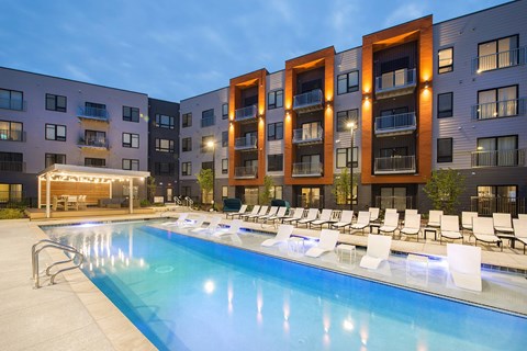2 Bedroom Luxury Apartments in Berkley Riverfront, MO - Union Berkley - Resort-Style Pool with Spacious Sundeck, Submerged and Poolside Lounge Chairs, and View of Apartment Buildings.