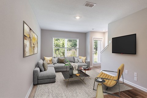 A living room with a grey couch, a yellow chair, and a painting on the wall.