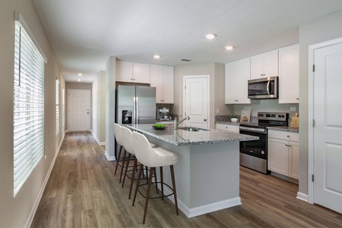 A kitchen with a bar area and white chairs.