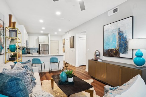 A living room with a white couch and a painting on the wall.