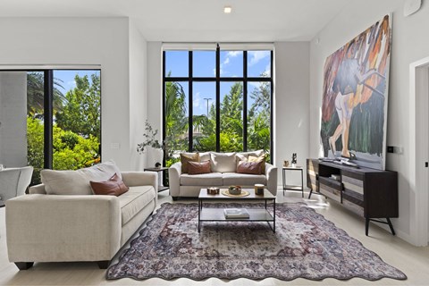 A living room with a large rug and a painting of a deer on the wall.
