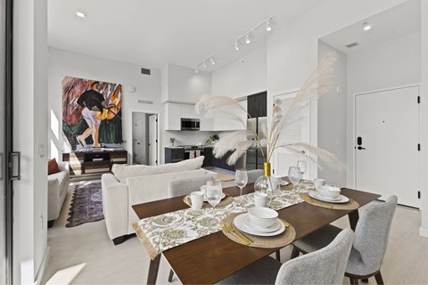 A dining room with a table set for two and a painting on the wall.