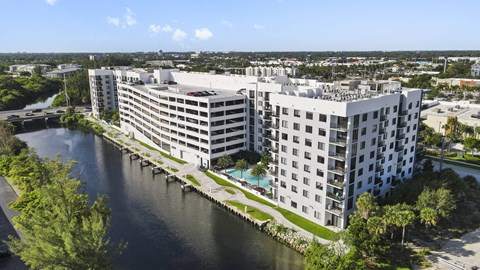 A large white building with a pool sits next to a body of water.