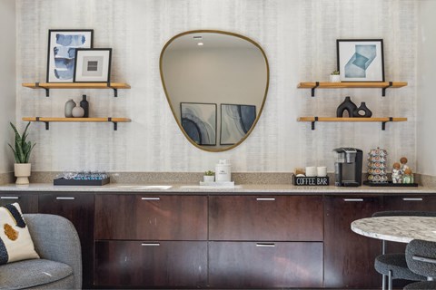 A modern kitchen with a grey chair and a round mirror above a counter.