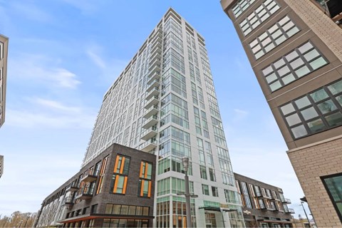A tall building with a glass facade stands between two shorter buildings.