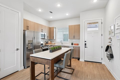 A kitchen with a table and chairs in front of a refrigerator.