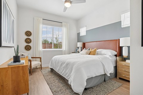 A bedroom with a large bed and a window with blinds.