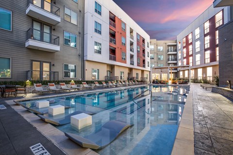 A swimming pool surrounded by apartment buildings at dusk.