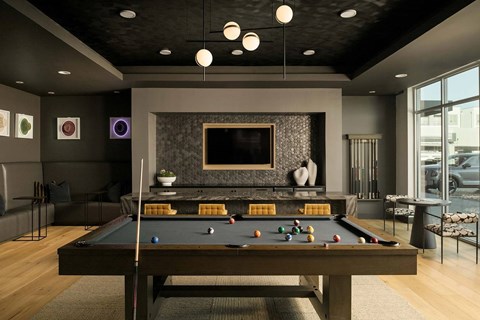 A pool table is in the middle of a room with a television and a fireplace.