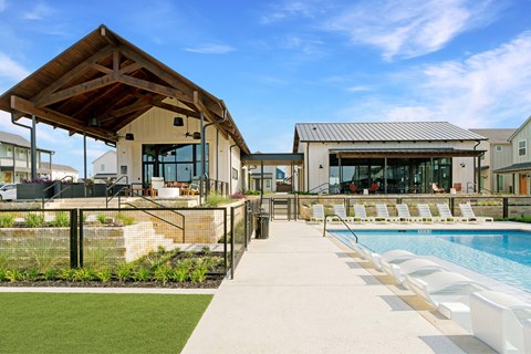 A pool area with a wooden pavilion and a metal roofed building.