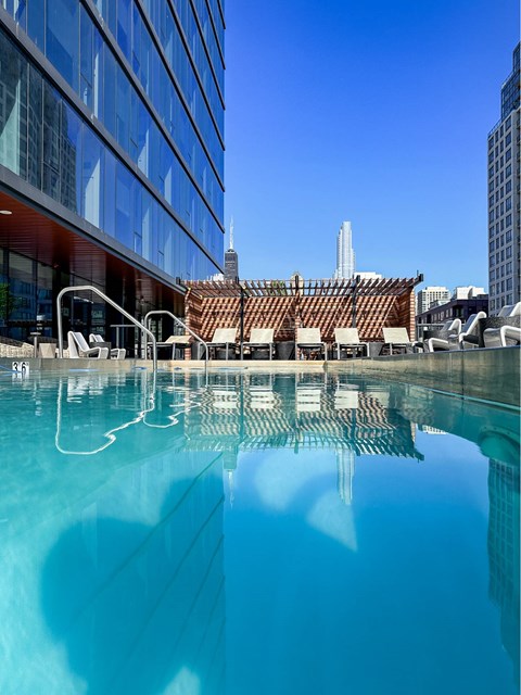 A swimming pool in front of a building with a clear blue sky.
