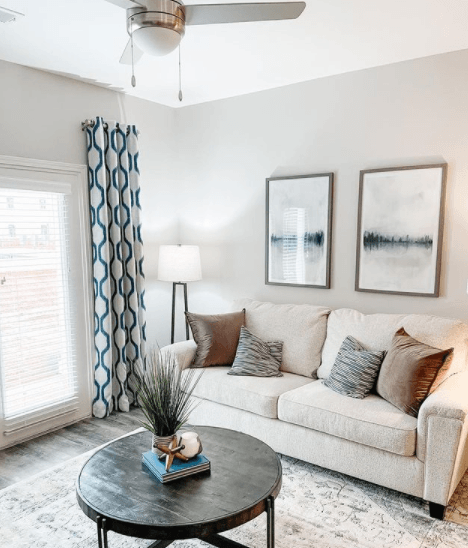 A living room with a white couch, a black coffee table, and two framed pictures on the wall.
