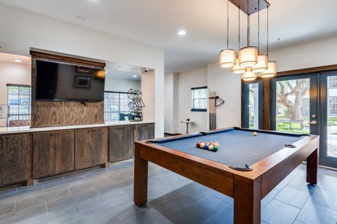 A pool table in a room with a television and a fireplace.