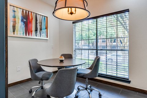 A dining room with a round table and grey chairs.