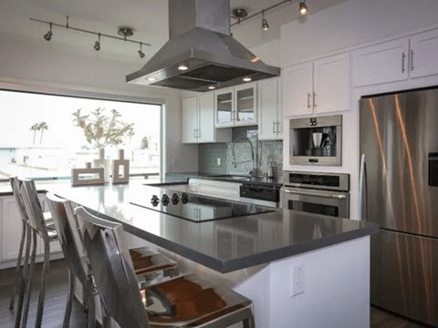 A modern kitchen with a stainless steel refrigerator and a glass island.